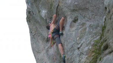 Genç adam dik kayalık dağ duvarına tırmanıyor. Erkek tırmanışçı zorlu rotayı aşar. Ekstrem spor konseptine dalmak.