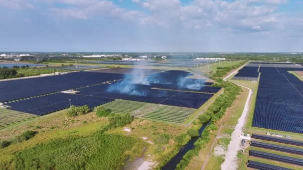太陽光発電パネルの行を持つ大規模な発電所での燃焼草の空中ビューは クリーンな電気エネルギーを生成します 再生可能エネルギー発電所における火災安全の概念 — ストック動画