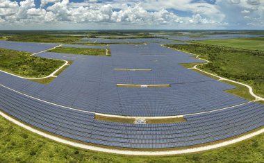 Temiz elektrik enerjisi üretmek için birçok sıra güneş fotovoltaik paneli bulunan sürdürülebilir büyük elektrik santralinin havadan görünüşü. Sıfır emisyon kavramı ile yenilenebilir elektrik.