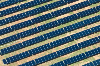 Temiz elektrik enerjisi üretmek için sıra sıra güneş fotovoltaik panelleri olan sürdürülebilir büyük elektrik santralinin havadan görünüşü. Sıfır emisyonlu yenilenebilir elektrik kavramı.