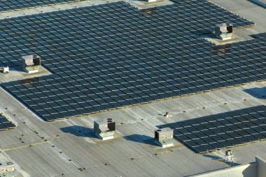 Sanayi binasının çatısına yeşil ekolojik elektrik üretmek için monte edilmiş mavi fotovoltaik panelli güneş enerjisi santralinin hava görüntüsü. Sürdürülebilir enerji konsepti üretimi.