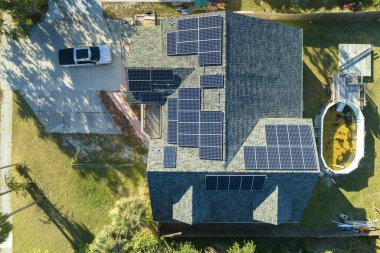 Aerial view of typical american building roof with rows of blue solar photovoltaic panels for producing clean ecological electric energy. Renewable electricity with zero emission concept.