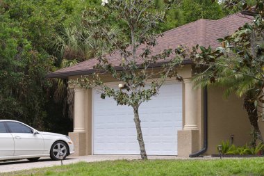 Car parked in front of wide garage double door on concrete driveway of new modern american house.
