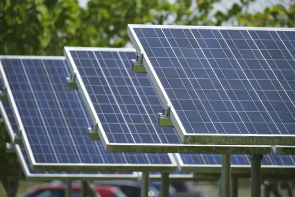 Solar panels installed on stand frame near parking lot for effective generation of clean electricity. Photovoltaic technology integrated in urban infrastructure for electric car charging.