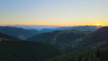 Güzel doğa manzarası. Vahşi dağlarda renkli günbatımının havadan görünüşü. Parlak batan güneşle aydınlatılmış karanlık çam ormanı..