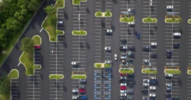 Park etmiş bir sürü arabası olan büyük bir otopark. Alışveriş merkezindeki büyük otopark. Araç yerleri ve yönleri için çizgiler ve işaretler var..