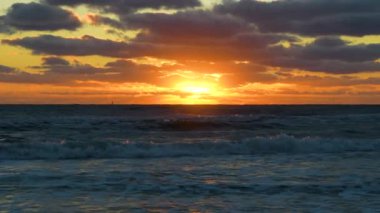 Ocean sunset landscape with soft evening sea water waves crushing on sandy beach.