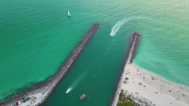 在美国萨拉索塔县威尼斯和诺科米斯海滩附近五彩缤纷的海水上航行的岩石防波堤和船只 — 图库视频影像