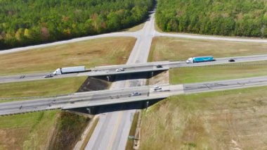 Aerial view of freeway overpass junction with fast moving traffic cars and trucks in American rural area. Interstate transportation infrastructure in USA.