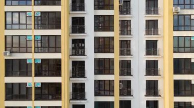 Birçok pencere ve balkonu olan modern yüksek apartman cephesinin mimari ayrıntıları.