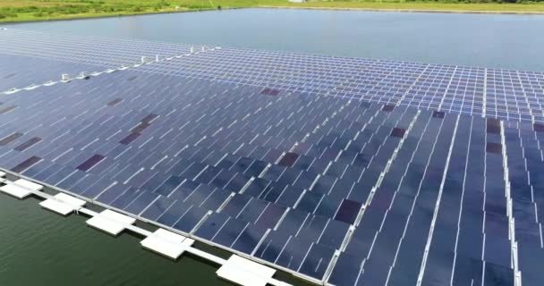 クリーンな電気エネルギーを生産するための太陽光パネルの多くの列を持つ浮遊太陽光発電所の上からの眺め 大気汚染のない水面の再生可能エネルギーの概念 — ストック動画