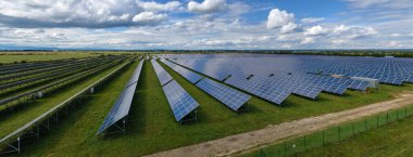 Temiz elektrik enerjisi üretmek için birçok sıra güneş fotovoltaik paneli bulunan sürdürülebilir büyük elektrik santralinin havadan görünüşü. Sıfır emisyon kavramı ile yenilenebilir elektrik.