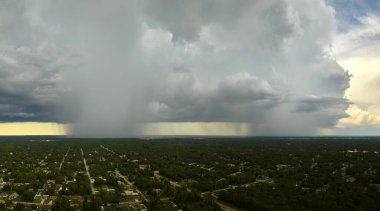 Landscape of dark ominous clouds forming on stormy sky during heavy thunderstorm over rural town area.