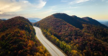 Empty free of vehicles I-40 freeway road leading to Asheville in North Carolina thru Appalachian mountains with yellow fall forest. High gas prices and energy crisis concept.