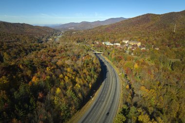 I-40 freeway road leading to Asheville in North Carolina thru Appalachian mountains with yellow fall forest and fast moving trucks and cars. Concept of high speed interstate transportation.