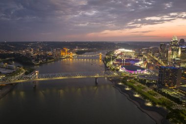 Ohio, ABD 'nin Cincinnati şehrinin şehir merkezindeki köprüde araç kullanan otoyol trafiği. Gece vakti ışıl ışıl parlayan yüksek ticari binalarla Amerikan şehri silueti.