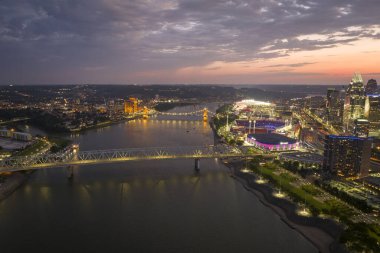 Ohio, ABD 'nin Cincinnati şehrinin şehir merkezindeki köprüde araç kullanan otoyol trafiği. Gece vakti ışıl ışıl parlayan yüksek ticari binalarla Amerikan şehri silueti.