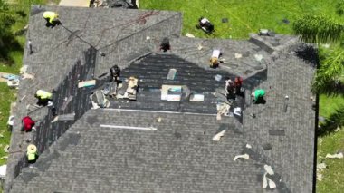 İnşaat işçileri çatı kaplaması olarak asfalt kiremitler kuruyor. Florida ev çatısı binası. Gayrimenkul geliştirme kavramı.