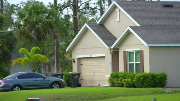 住宅コンセプト フロリダの典型的な現代的なアメリカのプライベートハウスは 屋根の上にアスファルトシングル 広いガレージドア 庭に緑の芝生で覆われています — ストック動画