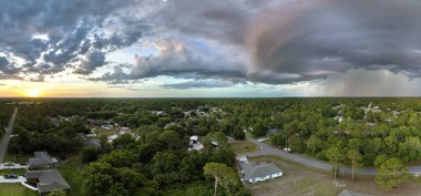 Dark stormy clouds forming on gloomy sky during heavy rainfall season over suburban town area in evening.