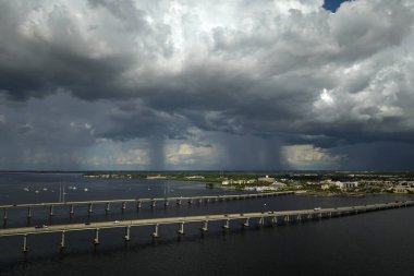 Stormy clouds forming from evaporating humidity of ocean water before thunderstorm over traffic bridge connecting Punta Gorda and Port Charlotte over Peace River. Bad weather conditions for driving. clipart