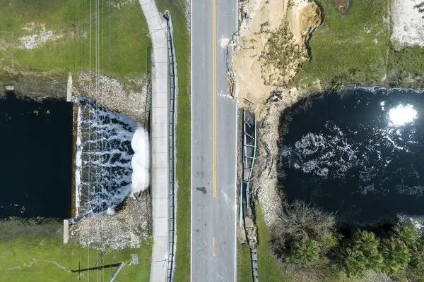 Repair of destroyed bridge after hurricane flood in Florida. Reconstruction of damaged road after flooding water washed away asphalt. Construction roadwork site.