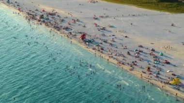 Sarasota, ABD 'de yumuşak beyaz kumlu ünlü Siesta Key plajı. Birçok insan sıcak körfez sularında yıkanmaktan ve gün batımında sıcak Florida güneşinin altında bronzlaşmaktan keyif alır..