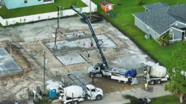 Yeni ev inşaatındaki işçilerin havadan görünüşü duvarlar ve çatı için beton döşeme temelleri döşemeye hazır..