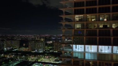 Florida, ABD 'deki Sunny Isles Beach City' de gece vakti aydınlık bir konut binasının yüksek açılı görüntüsü. Modern Amerikan kentsel bölgesinde konut geliştirme.