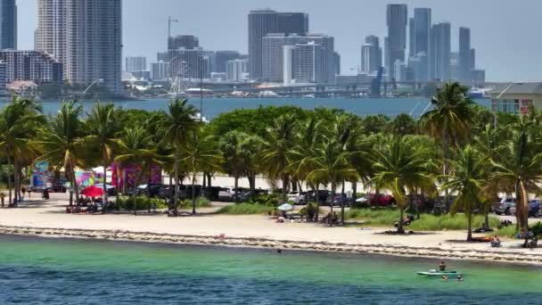 マイアミビーチの上から見ると アメリカ合衆国フロリダ州マイアミ ブリッケル市のダウンタウンにあるリラックスした観光客や高層ビルがあります ビジネス金融地区を持つウォーターフロント アメリカン メガポリス — ストック動画