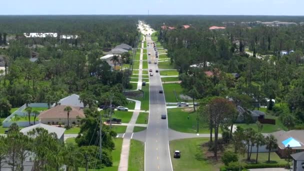 フロリダ州のアメリカの小さな町で交通車を運転する農村道路 静かな住宅街の緑の木と郊外の通りの間の私的な家 — ストック動画