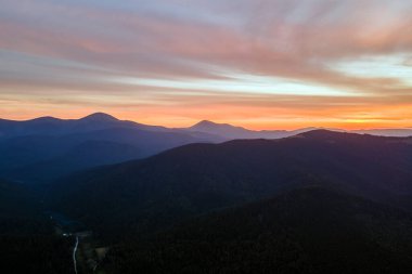 Gün batımında puslu tepeleri ve sisli vadisi olan güzel dağ panoramik manzarası.