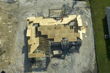 Florida 'nın banliyö bölgesinde ahşap iskeleti olan bitmemiş bir konutun çatı inşaatında çalışan inşaatçılar. Konut geliştirme kavramı.