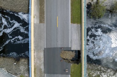 Sel suları asfaltı yıktıktan sonra hasar gören yol köprüsü nehirle yıkıldı. Yıkılmış ulaşım altyapısının yeniden inşası.