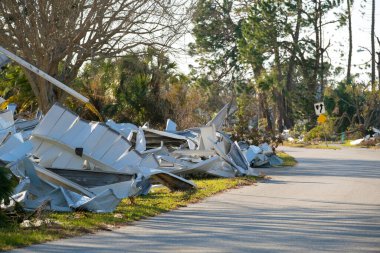 Kasırganın yol kenarındaki metal çöpler Florida yerleşim bölgesindeki evlere ağır hasar vermiş. Doğal afetten sonra.