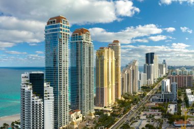 Sunny Isles Beach City 'deki Atlantik Okyanusu kıyısındaki lüks otellerin ve apartmanların manzarası. Kalabalık trafiği olan bir şehir caddesi. Güney Florida 'daki Amerikan turizm altyapısı.