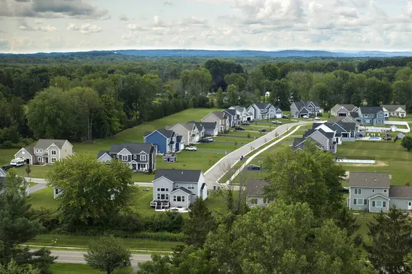 Upscale suburban homes with large backyards and green grassy lawns in summer season. Private residential houses in rural suburban sprawl area in Rochester, New York.