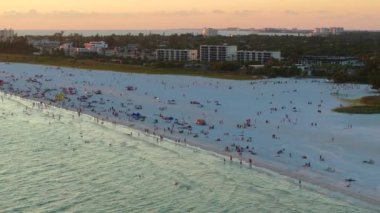Aerial view of Siesta Key beach in Sarasota, USA. Many people enjoing vacation time swimming in gulf water and relaxing on warm Florida sun at sunset.