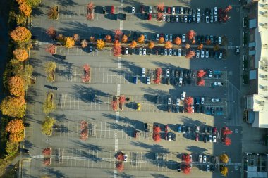Hava manzaralı alışveriş merkezi ve park yerinde park yerleri ve yönler için çizgiler ve işaretler olan bir sürü renkli araba. Bir alışveriş merkezinin önünde araçlar için yer.
