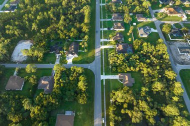 Aerial view of american small town in Florida with private homes between green palm trees and suburban streets in quiet residential area.