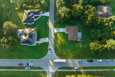 Sabahın erken saatlerinde Amerikan sarı okul otobüsünün kaldırımdaki otobüs durağından çocukları aldığı hava görüntüsü. ABD 'de toplu taşıma.