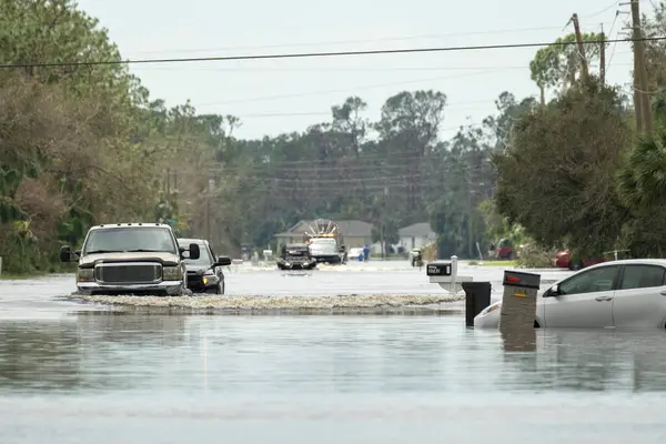 stock image Flooded town street with moving cars submerged under water in Florida residential area after hurricane Ian landfall. Consequences of natural disaster.