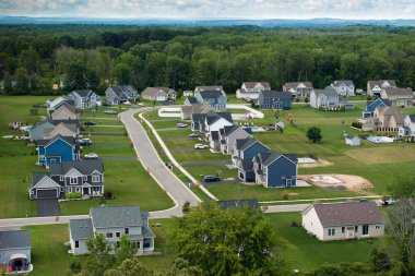 Düşük yoğunluklu iki katlı özel evler Rochester, New York 'un dışındaki kırsal yerleşim yerlerinde. Büyük arsa büyüklüğünde lüks banliyö evleri ve yaz mevsiminde yeşil çimenli çimenler.