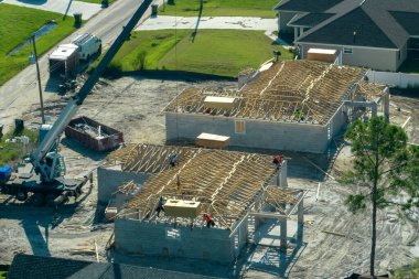Profesyonel inşaatçılar ve vinç kamyonu Florida kırsal kesiminde ahşap çerçeveli bitmemiş bir banliyö evinin çatı inşaatında çalışıyor. Amerika 'da konut geliştirme kavramı.