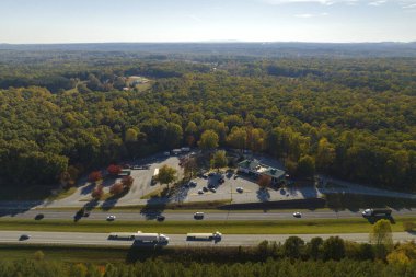 Top view of large rest area near busy multilane american freeway with fast moving cars and trucks. Recreational resting place during interstate traveling.