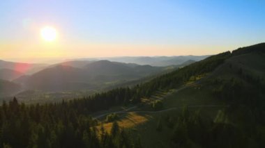 Güzel doğa manzarası. Vahşi dağlarda renkli günbatımının havadan görünüşü. Parlak batan güneşle aydınlanan karanlık toprak yol.