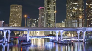 Florida, ABD 'nin Tampa şehrinin şehir merkezindeki gece şehir manzarası. Köprüde arabaları süren ve modern Amerikan megapolis 'inde gökdelenleri aydınlatan gökdelenler.