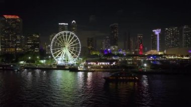 Biscayne Körfezi suları ve Brickell 'in yüksek aydınlatmalı gökdelenleri ve finans merkezleri ile birlikte Bayside Pazarı' ndaki Miami Gözlem Çarkı 'nın gece kentsel manzarası..