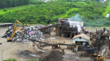Pençe vinç manipülatörlü hurdalık hurdalığı geri dönüşümlü atıkları kaldırıyor ve yok ediyor. Atık alanında nakliye ekipmanları.