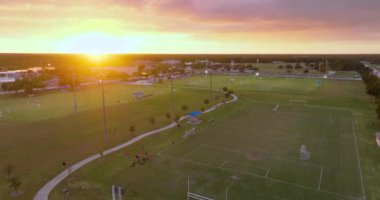 Kuzey Port, Florida 'da halk spor sahasında gün batımında çimen futbol stadyumunda futbol oynayan insanlarla aydınlandı. Açık hava aktiviteleri konsepti.